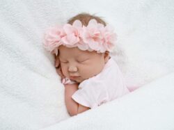 baby in white shirt lying on white textile