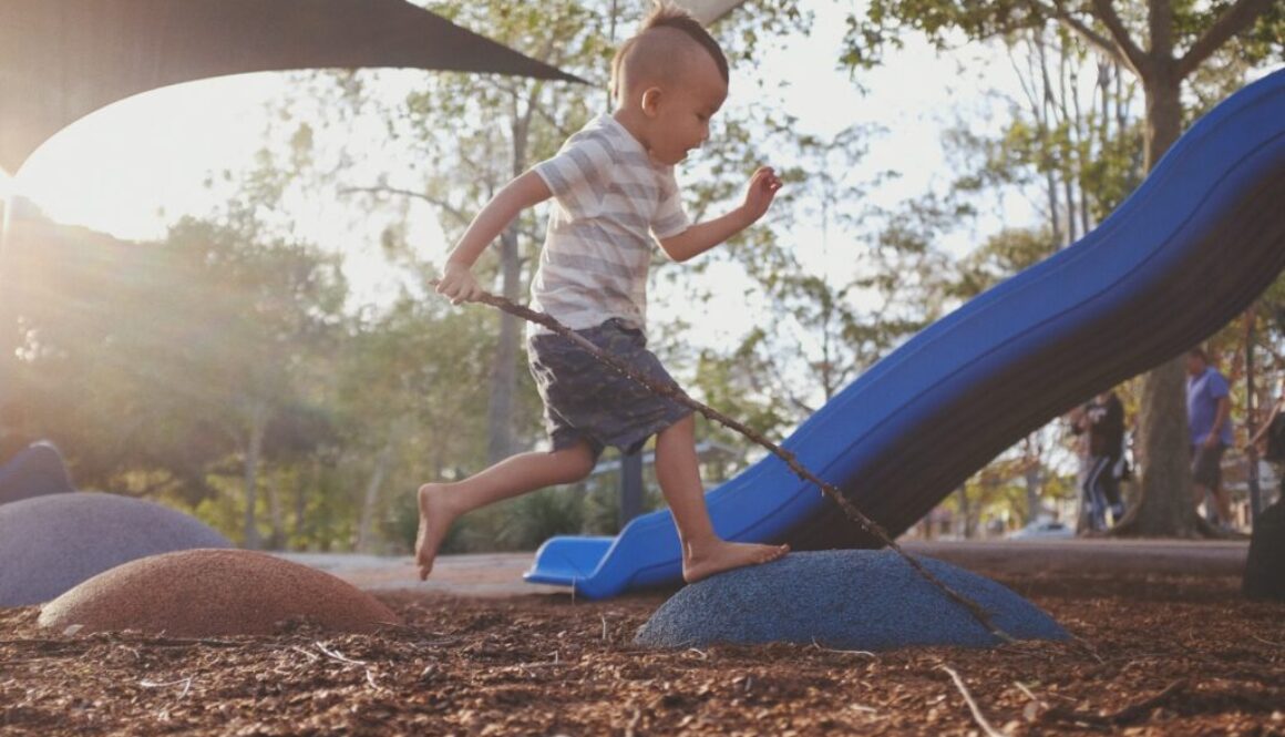 boy stepping on rocks in playground during daytime