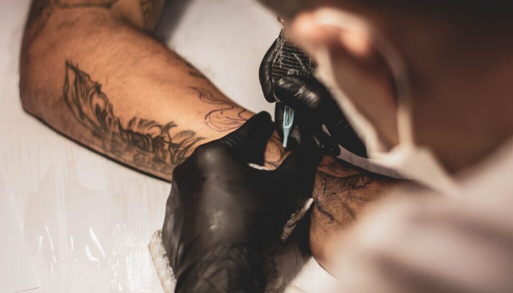 shallow focus photo of person tattooing person's right arm