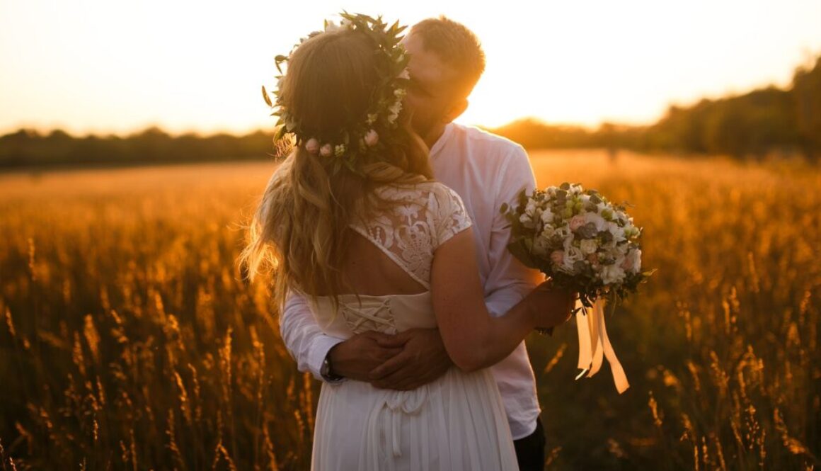 Man and Woman Standing in Front of Brown Grass Field Kissing Each Other