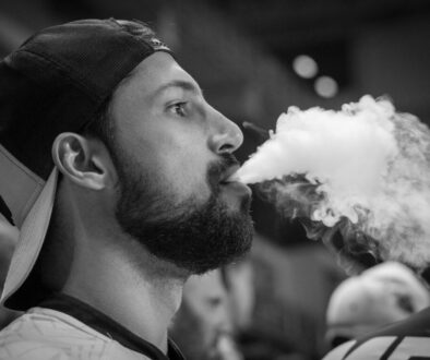 Grayscale Photography of Man Wearing Cap With Smoke on Mouth